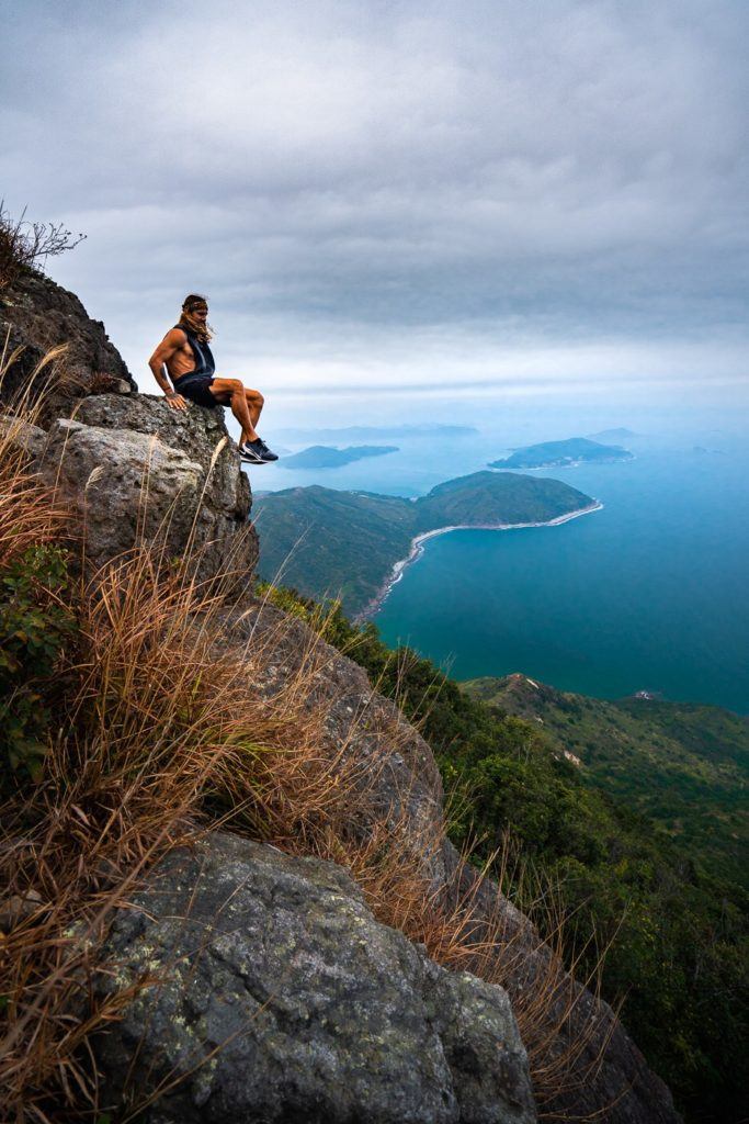 ein Mann, der auf einem Berg am Meer sitzt.