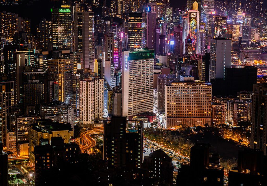 ein Blick auf eine Stadt bei Nacht von der Spitze eines Gebäudes.