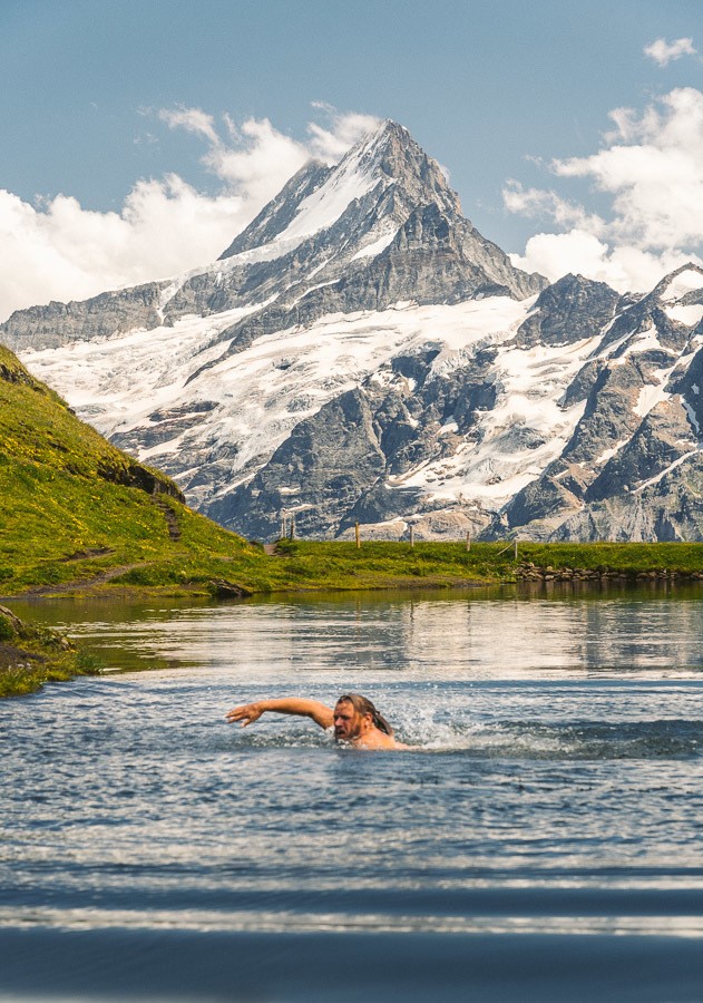 ein Mann, der in einem See schwimmt, mit einem Berg im Hintergrund.