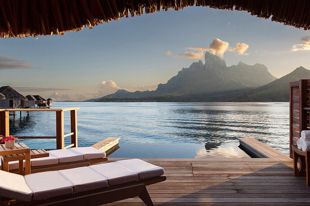 Eine Terrasse mit Liegestühlen und Blick auf das Wasser in den Überwasserbungalows Französisch-Polynesiens.