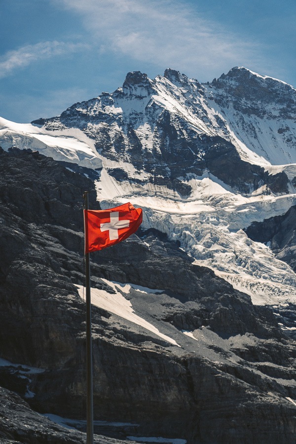 Eine Schweizer Flagge weht vor einem Berg.