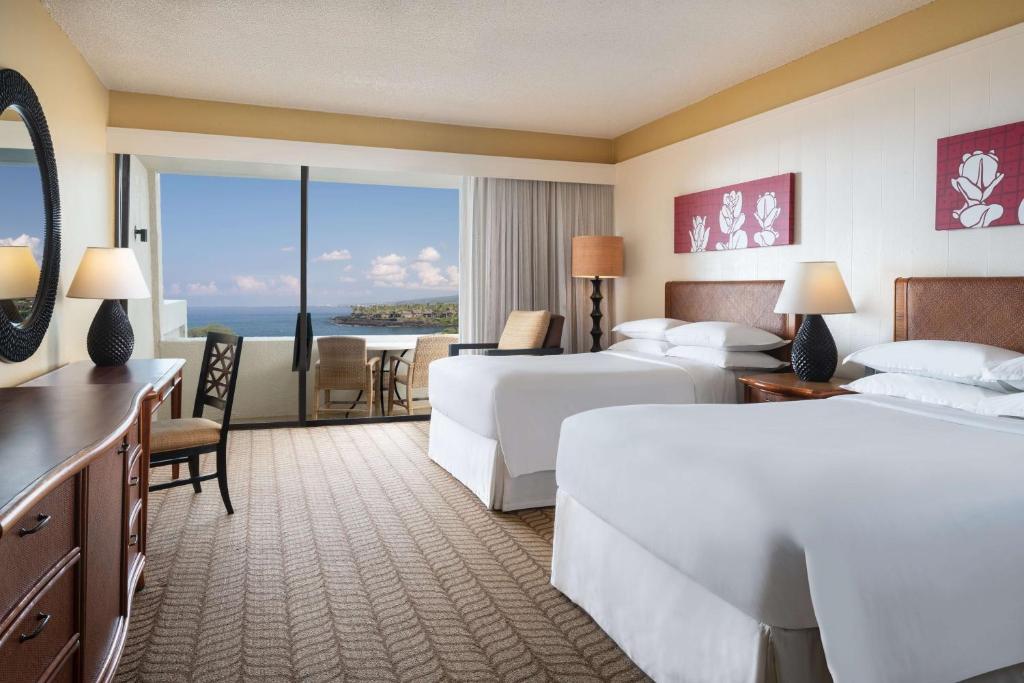 Ein Hotelzimmer mit zwei Betten und Blick auf das Meer.