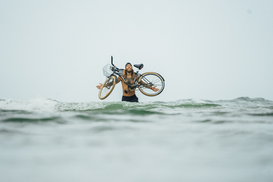 Ein Mann hält ein Fahrrad im Meer.