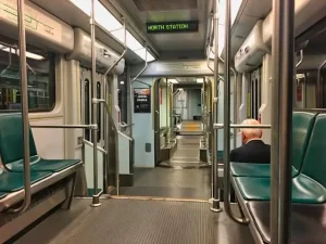 Intérieur d’une rame du métro de Miami avec sièges vides et un passager assis, montrant l’ambiance calme et l’aménagement spacieux.
