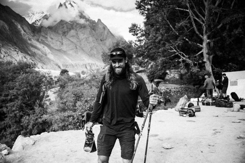 ein Mann mit langen Haaren und Bart, der Skier trägt