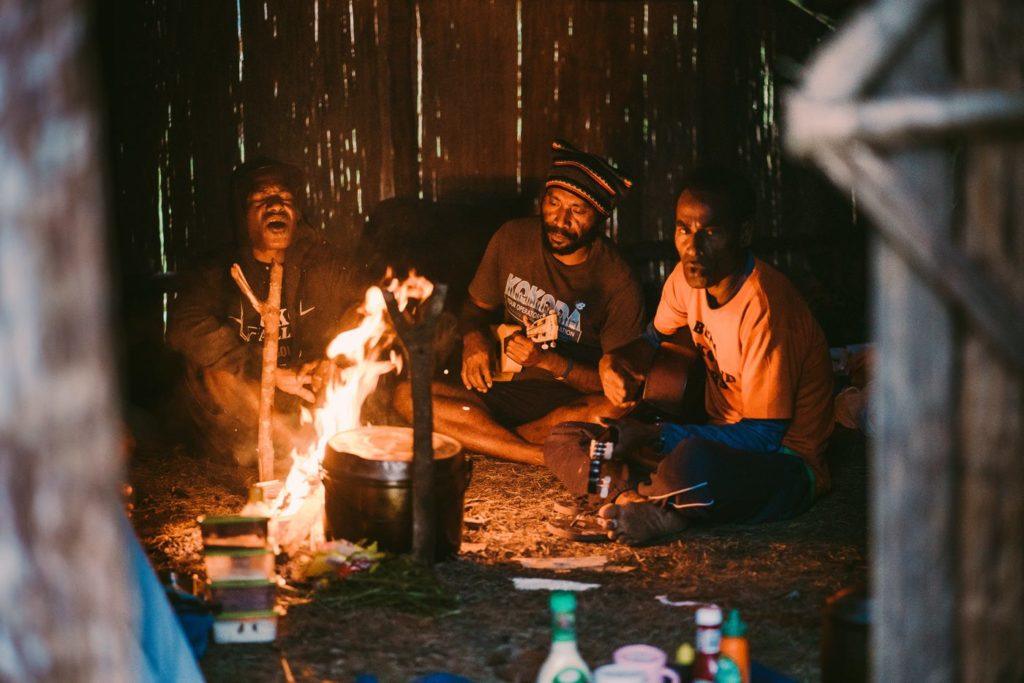 Eine Gruppe von Menschen sitzt um ein Lagerfeuer.